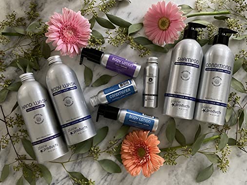 Plaine Products shampoo, body wash and other product aluminum containers arranged on a table with flowers and plant clippings.